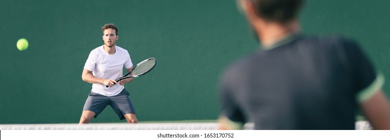 Tennis players playing on green court man focused on other player hitting ball with racket panoramic. Men sport athletes playing tennis match. Two professional tennis players outdoor during game.