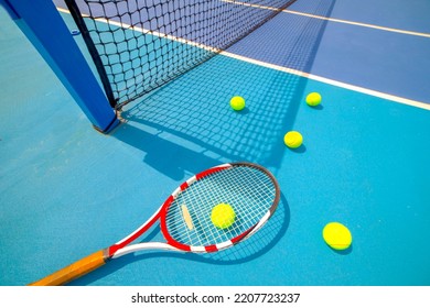 Tennis racket, ball and tennis ball box on hard blue court