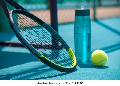 Tennis racket, ball and water bottle on hard blue court - Powered by Shutterstock