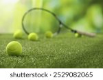 Tennis racket and balls on green artificial grass, selective focus