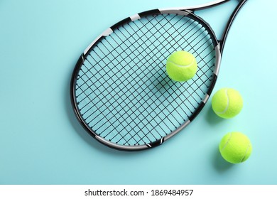 Tennis racket and balls on light blue background, flat lay. Sports equipment