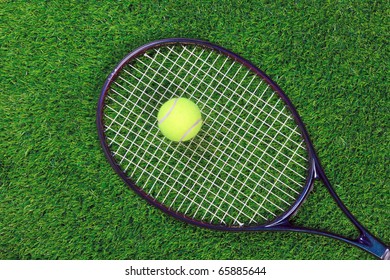 A Tennis Raquet Or Racket And Yellow Ball On Grass.