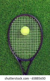 A Tennis Raquet Or Racket And Yellow Ball On Grass.