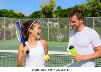 Tennis sport - couple relaxing after playing game of tennis outside in summer. Happy smiling friends on outdoor tennis court living healthy active fitness lifestyle. Woman and man athletes. - Powered by Shutterstock