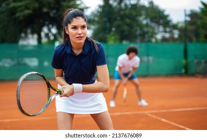 Tennis sport people concept. Mixed doubles player hitting tennis ball with partner standing near net - Powered by Shutterstock