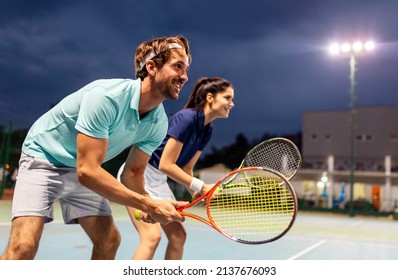 Tennis sport people concept. Mixed doubles player hitting tennis ball with partner standing near net - Powered by Shutterstock