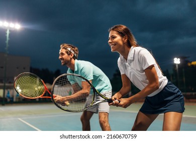 Tennis sport people concept. Mixed doubles player hitting tennis ball with partner standing near net - Powered by Shutterstock