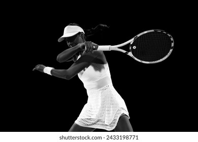 Tennis sportswoman in motion, about to strike shot to ball on court against black studio background. Monochrome filter. Concept of women in sport, active lifestyles, tournaments and events, movement. - Powered by Shutterstock