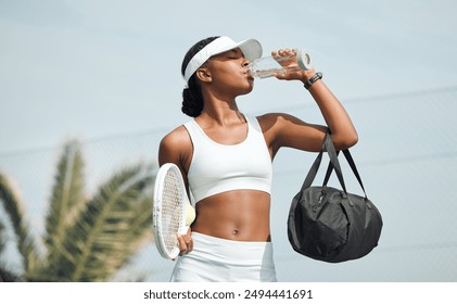 Tennis, water bottle and black woman on court, sports and fitness with nutrition, wellness and workout. African person, outdoor and athlete with liquid, racket and training with break, rest or health - Powered by Shutterstock