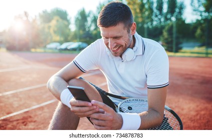 Tennis. Young tennis player take a rest after training, having fun with mobile phone. Sport, recreation concept - Powered by Shutterstock