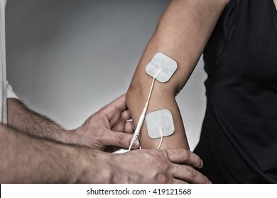TENS treatment in physical therapy - therapist placing electrodes onto patient's elbow