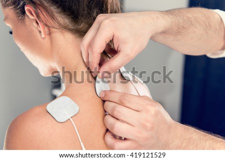 TENS treatment in physical therapy - therapist placing electrodes onto patient