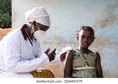 Tense little African schoolgirl is waiting for her pediatrician to inject a dose of vaccine into her arm