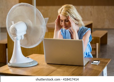 Tense woman sitting in desk with laptop in office - Powered by Shutterstock