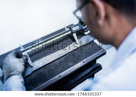 Tensile Testing, Engineer using digital vernier to measure the elongation period of the material specimen after finished tension test in the industrial factory laboratory. Mechanical properties test.