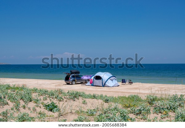 A tent camp on a sandy beach near the\
sea. Camping, summer camp, traveling by\
car.