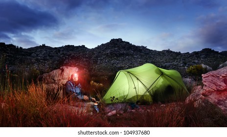 Tent Camping Wilderness Adventure Man With Headlamp And Gas Burner In The Mountains Cooking Food At Night While Looking Into Panorama Of The Great Outdoors