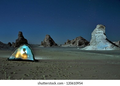 Tent With Girl In Back Light In Egyptian Sahara. Photo Taken At  White Desert In Egypt At Night, Under A Full Moon Light. Limestone Rocks In The Background Landscape