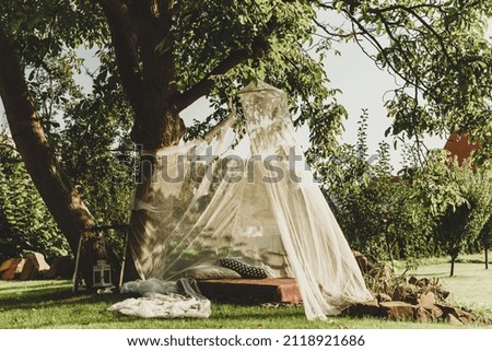 tent made of transparent fabric, trestle bed and pillows under the tree 