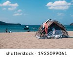 A tent pitched at a public beach, in the middle of the scorching day. Clothes and towels are on top outside to dry. Camping in Nasugbu, Batangas, Philippines.