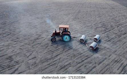 Teplik, Ukraine, April 21, 2020. An Old Tractor That Carries Trailed Roller Blades To Sow Crops. Drought And Dust Rising From The Air From Machinery.