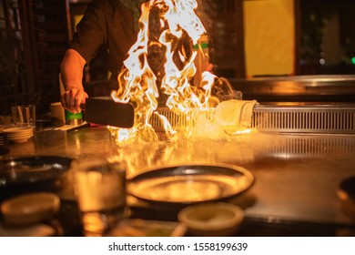 Teppanyaki Chef Preparing Metal Plate With Flaming Fire Ready For Cooking Japanese Cuisine.