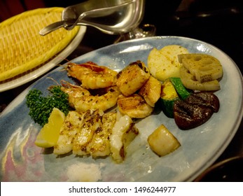 Teppanyaki Fried Fancy Seafood Dinner With Salmon Steak, Shrimps, Scallop, Kinpira Renkon Lotus Root And Squid Served On The Restaurant Table, Silver Saucer In Background