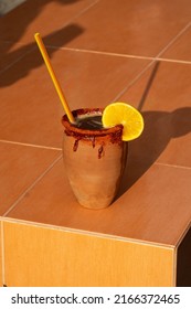 Tequila "cantarito" cocktail served in a clay cup with ice and lime.