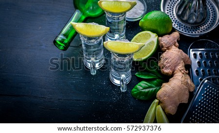 Tequila with lime, lemon, and salt on a black background Wooden. Free space for text . Top view.