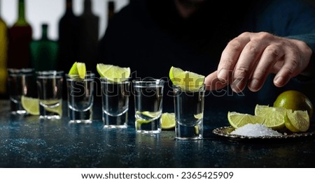 Tequila with salt and lime slices on a dark blue table.