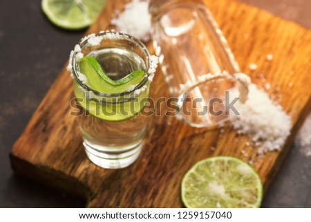Tequila shot with lime and salt closeup on a cutting board. An empty shot of tequila. Selective focus