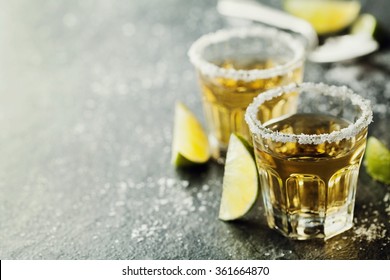 Tequila shot with lime and sea salt on black table, selective focus