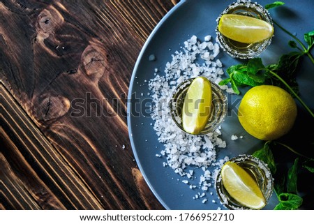 Tequila shot with lime and sea salt on grey plate