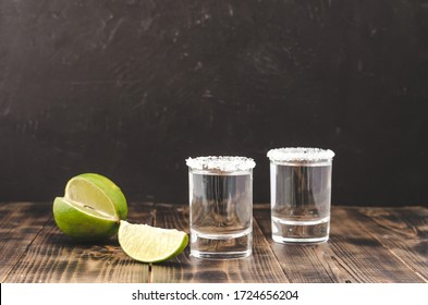 Tequila shot with lime slices and salt on wooden table/Tequila shots and lime slice on wooden table.With copy space on black background.