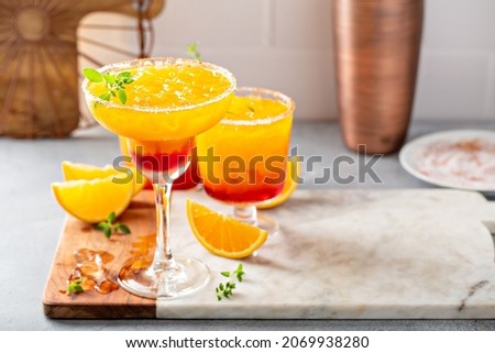 Tequila sunrise cocktails with orange wedges in a variety of glasses