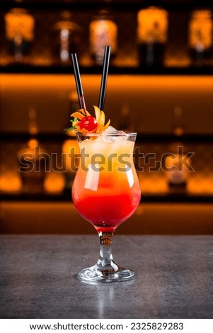 Tequila Sunrise with grenadine, orange juice and ice cubes. Fresh alcoholic cocktail with orange and ice. Vertical orientation.