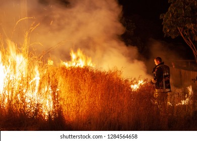 Teralba, NSW/Australia - October 24, 2012: Fireman Or Firefighter Backburning And Extinguishing A Wildfire Grass And Bushfire. Editorial Action In Landscape Format.