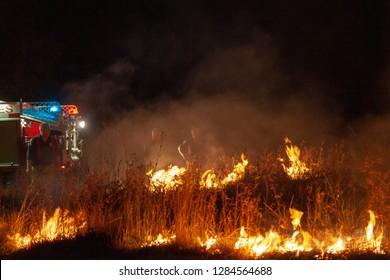 Teralba, NSW/Australia - October 24, 2012: Fire Truck And Firemen Or Firefighters Backburning And Extinguishing A Wildfire Grass And Bushfire Editorial Action In Landscape Format.