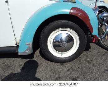 Teresopolis, RJ, Brazil - March 20th 2022 - Wheel and tyre of a Volkswagen Beetle. Rusty car with light blue fenders and white side. Tyre with a white strip. Chrome hubcap. Vintage old classic car.