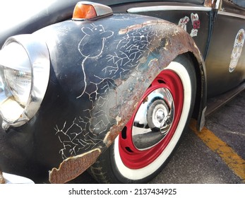 Teresopolis, RJ, Brazil - March 20th 2022 - Red Wheel and tyre of a Volkswagen black Beetle. Rusty decorated car. Tyre with a white strip. Chrome hubcap and a red wheel. Car porky taken care of.