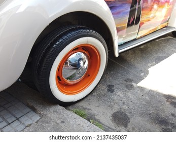Teresopolis, RJ, Brazil - March 20th 2022 - Wheel and tyre of a white Volkswagen Beetle. Tyre with a white strip. Chrome hubcap. Orange wheel. Classic vintage old car. 