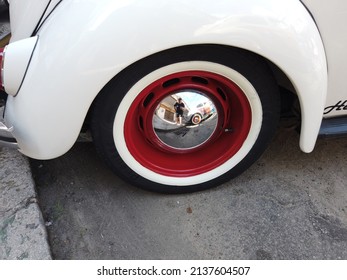 Teresopolis, RJ, Brazil - March 20th 2022 - Wheel and tyre of a white Volkswagen Beetle. Tyre with a white strip. Chrome hubcap. Red wheel. Classic vintage old car. 