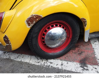 Teresopolis, RJ, Brazil - March 20th 2022 - Wheel and tyre of a Volkswagen Beetle. Yellow rusty car. Red wheel. Chrome hubcap. Vintage old classic car.