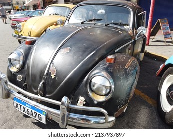 Teresopolis, RJ, Brazil - March 20th 2022 -  Volkswagen black Beetle. Rusty decorated car.   Chrome hubcap and a red wheel. Car porky taken care of, damaged with lots of rust. Old classic retro car.