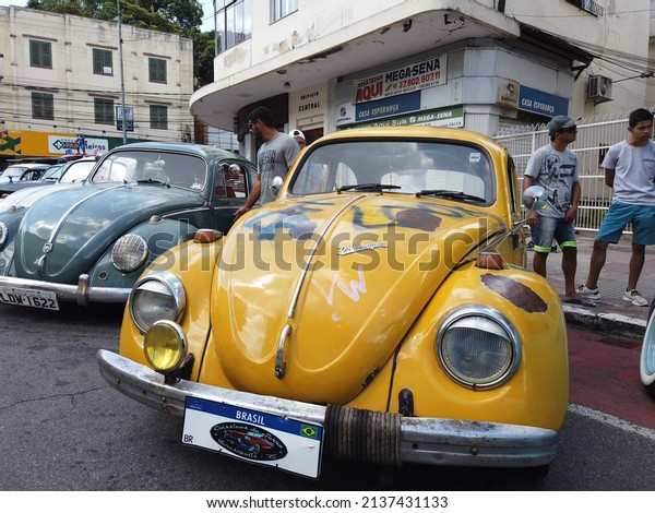 Teresopolis, RJ, Brazil - March 20th 2022 -\
Volkswagen Beetle vintage car year 1970. Red wheels. Yellow colour,\
with rust and drawings. Rear luggage carrier with a skateboard.\
Vacation and\
holidays.