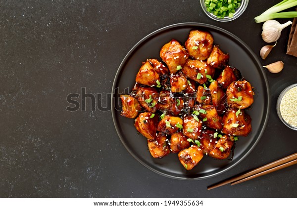 Teriyaki chicken on plate over black\
stone background with free text space. Top view, flat\
lay\
