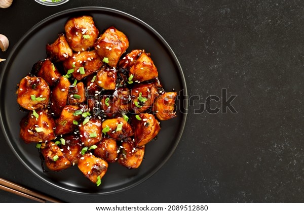 Teriyaki chicken on plate over black stone\
background. Top view, flat\
lay