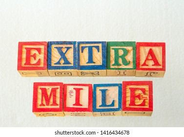 The Term Extra Mile Visually Displayed On A White Background Using Colorful Wooden Blocks Image With Copy Space In Landscape Format