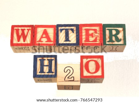 The term water h2o displayed visually using colorful wooden to blocks on a white background in landscape format with copy space