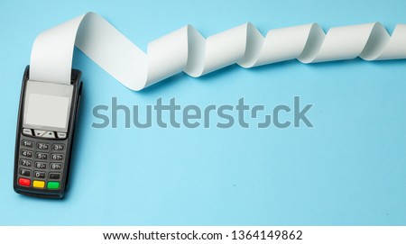 Terminal cash register machine POS for payments and long roll cash tape on blue background. Copy space for text